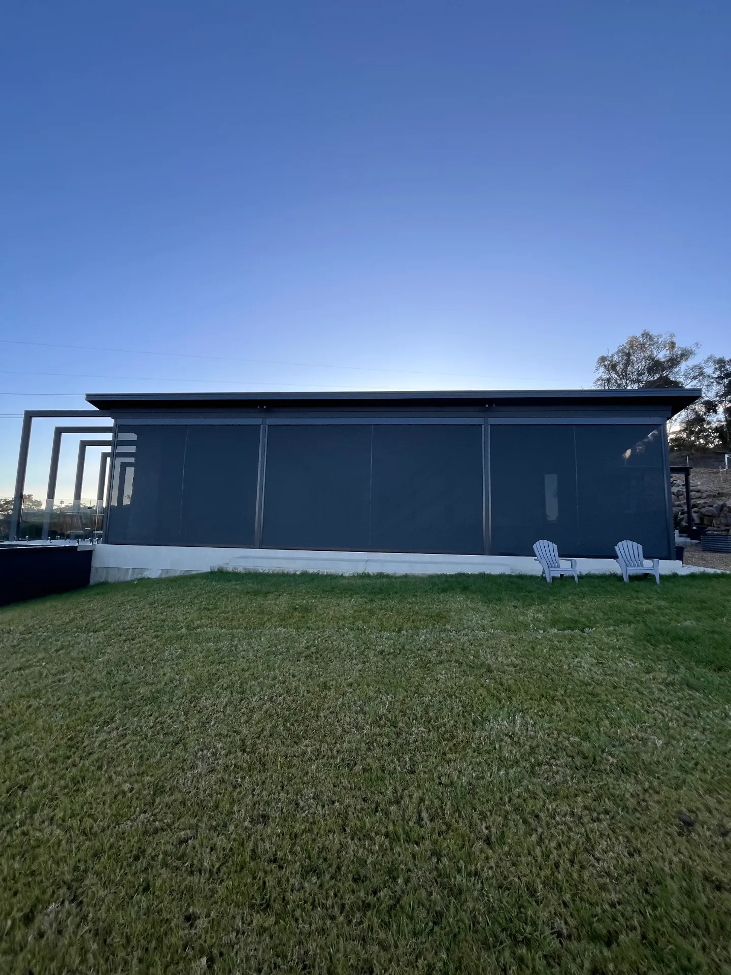 Modern home with full-width zipscreens at dusk