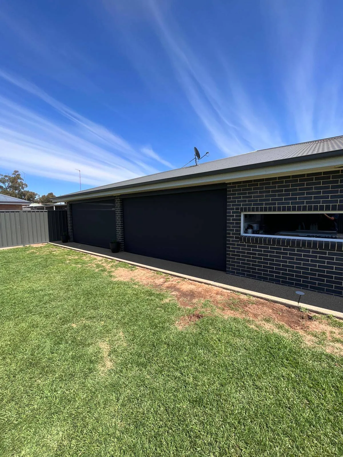 Black zipscreen installation on brick house patio
