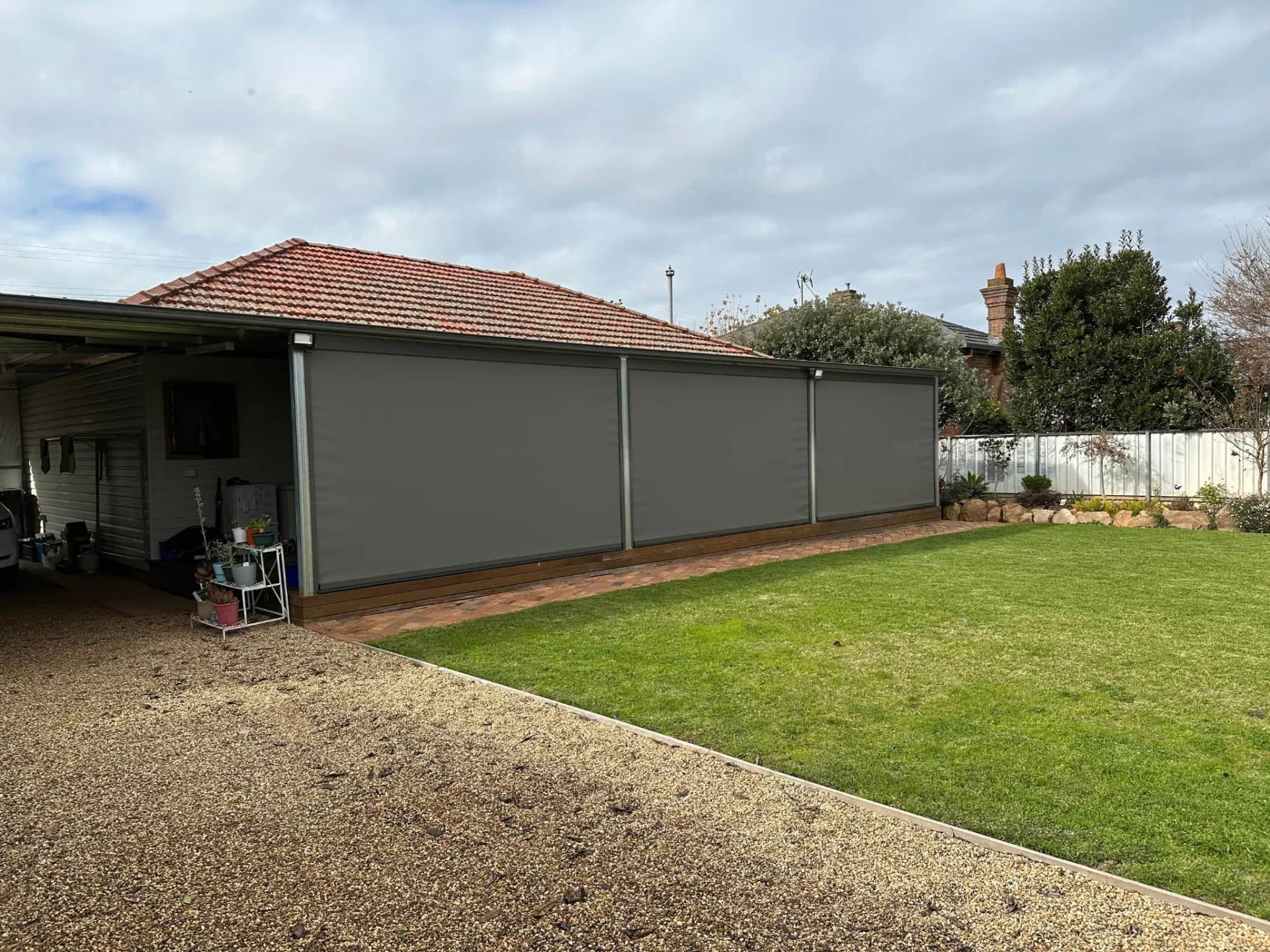 Grey outdoor blinds protecting a carport area