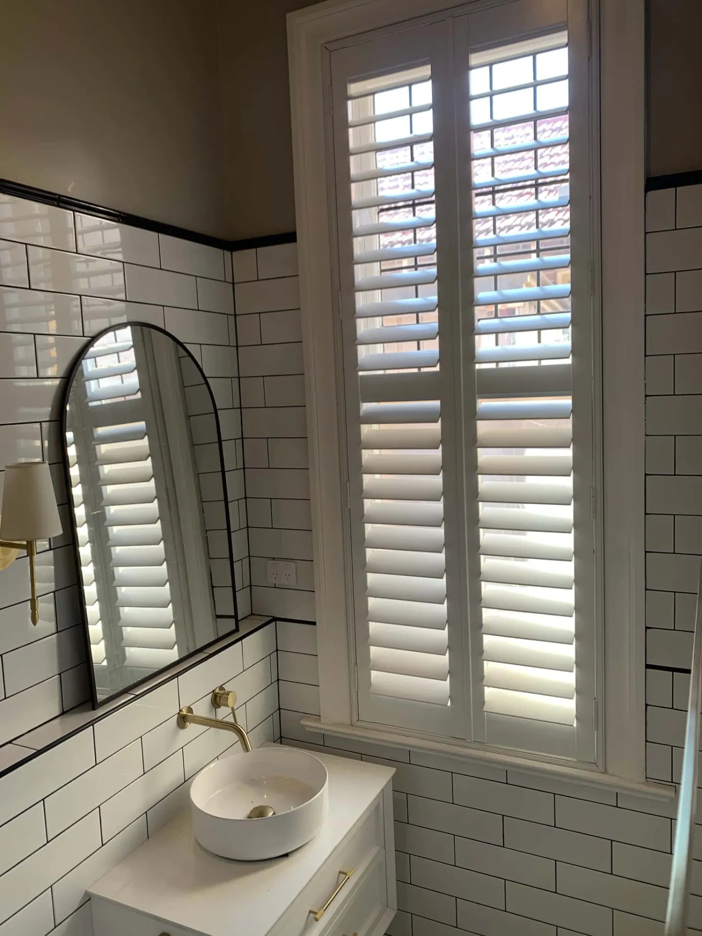 White plantation shutters in modern bathroom with subway tiles