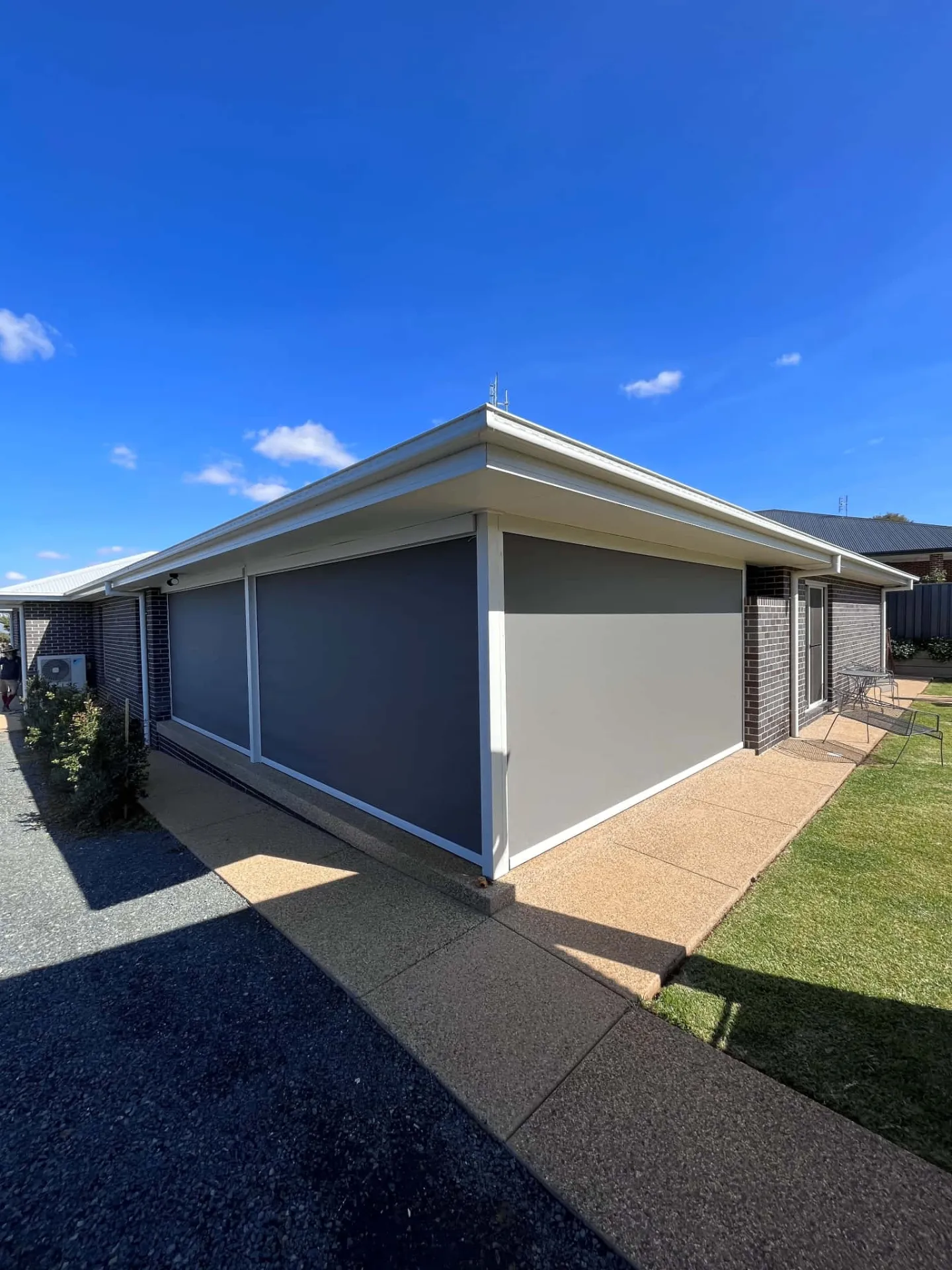 Large format outdoor zipscreens on brick home exterior