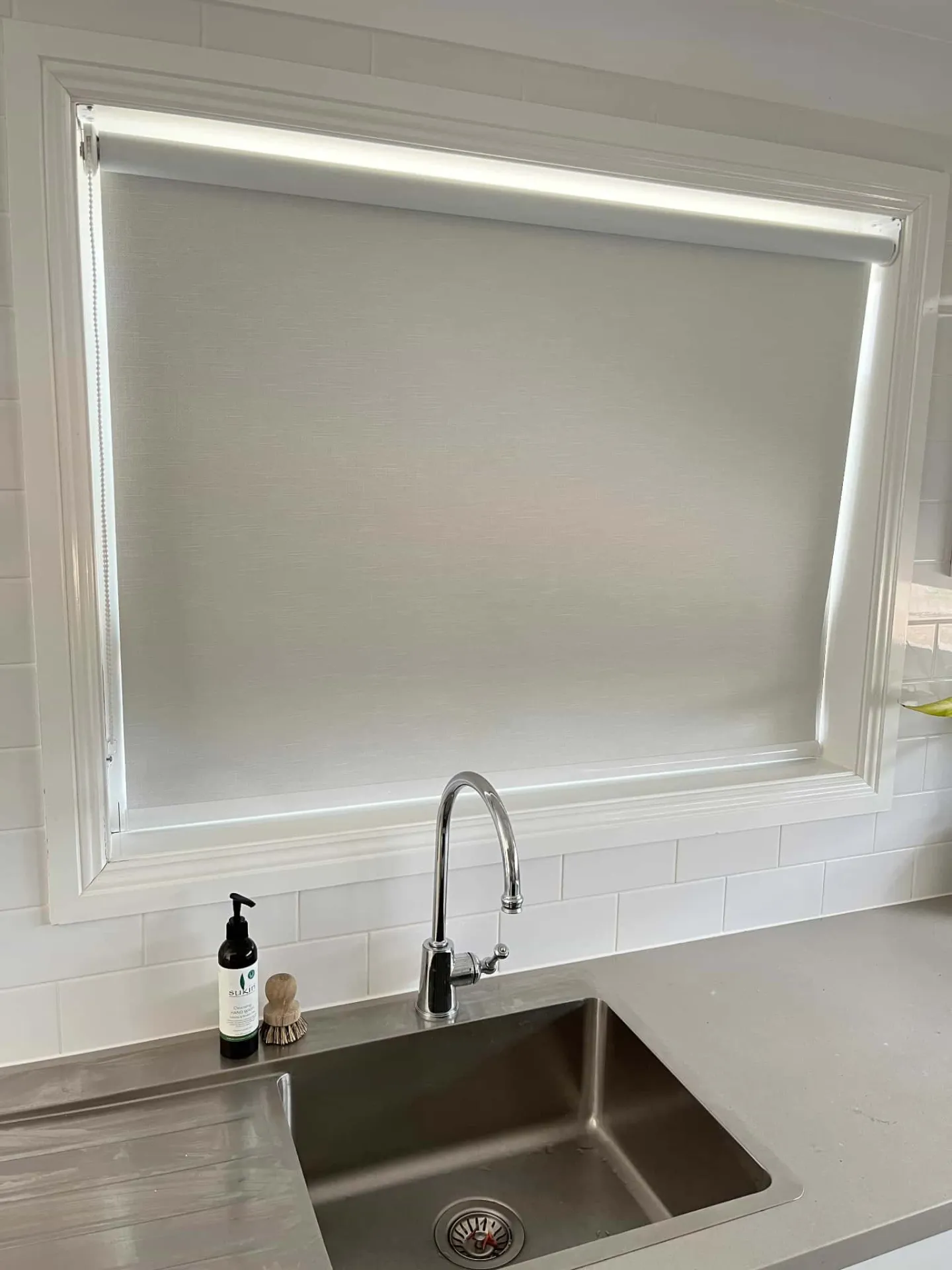 Roller blind above kitchen sink with clean white finish
